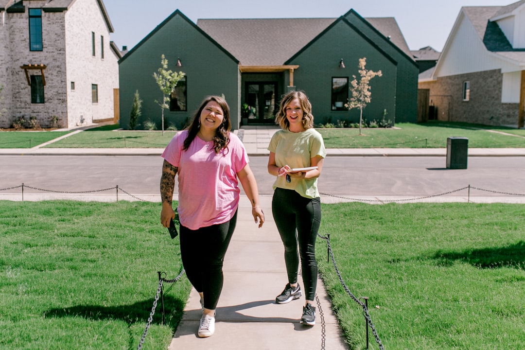 A cheerful couple stands proudly in front of their beautiful modern home, holding up a set of keys to celebrate their successful property sale.