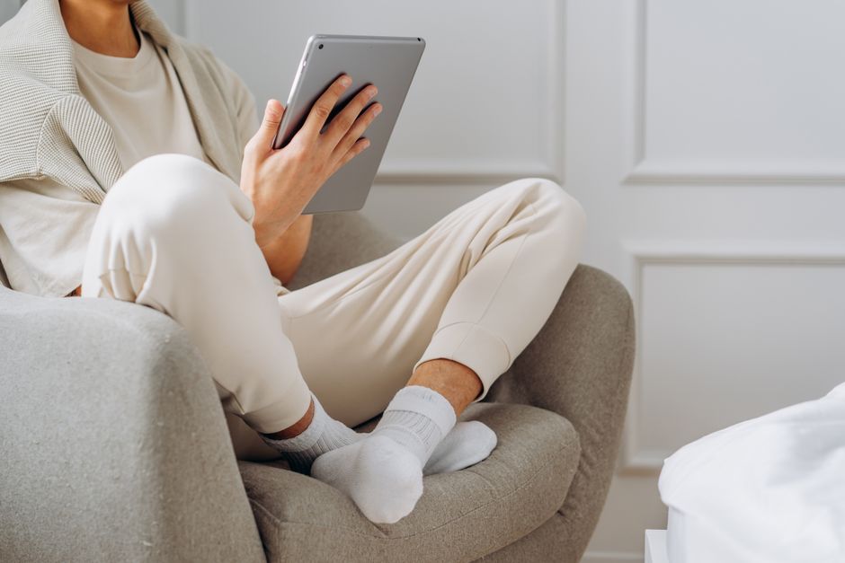 Close-up of a person's hands holding a tablet, browsing through an online portal of beautiful home listings, representing a buyer reached through targeted digital marketing.